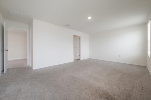 carpeted spare room featuring baseboards, visible vents, and recessed lighting