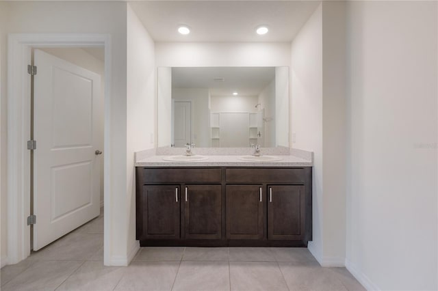 bathroom featuring tile patterned floors, double vanity, a sink, and walk in shower