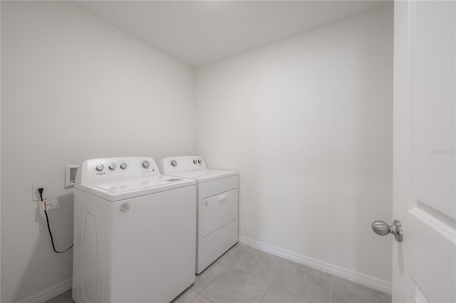 laundry room with light tile patterned floors, washing machine and clothes dryer, laundry area, and baseboards