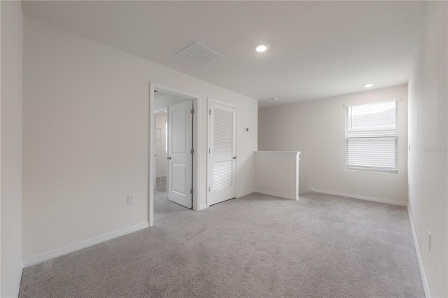 spare room with visible vents, baseboards, and light carpet