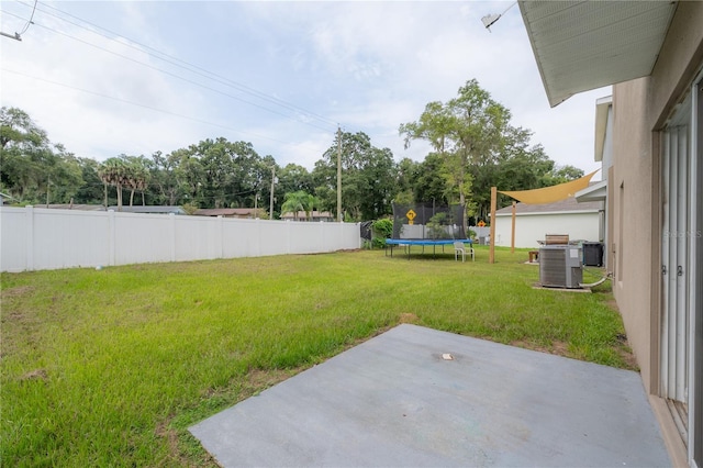 view of yard featuring a trampoline, a patio area, central air condition unit, and fence