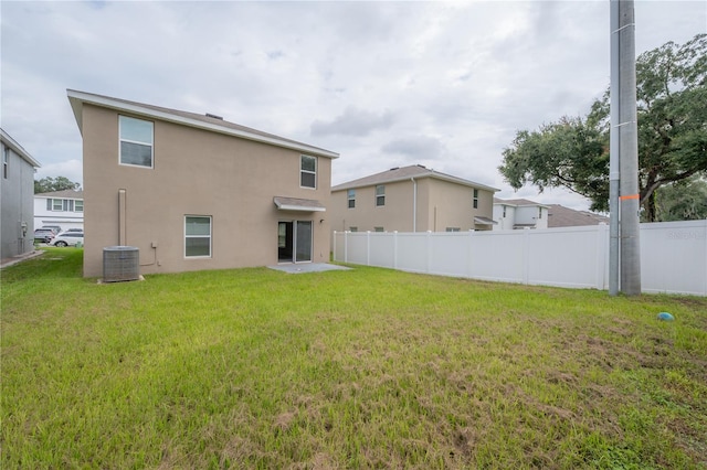 rear view of property featuring stucco siding, cooling unit, fence, and a lawn