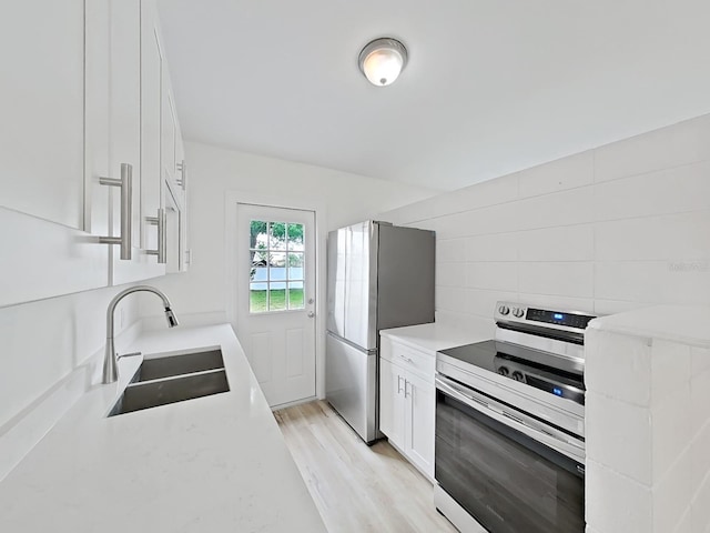 5772 4th Ave N, Saint Petersburg, FL 33710 - kitchen featuring light wood-style flooring, light countertops, white cabinets, stainless steel appliances, and a sink