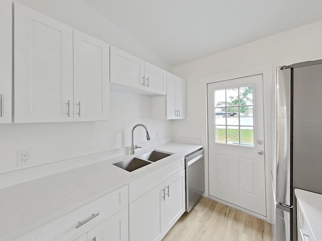 5772 4th Ave N, Saint Petersburg, FL 33710 - kitchen with light wood-type flooring, light countertops, white cabinetry, stainless steel appliances, and a sink