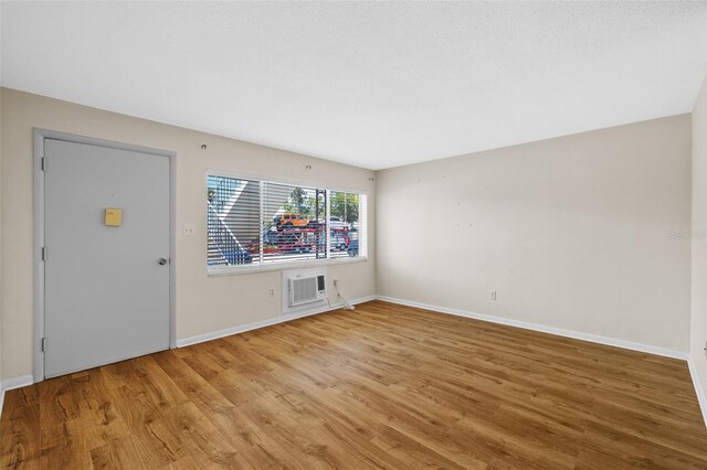 2366 Shelley St Unit 7, Clearwater, FL 33765 - unfurnished living room featuring baseboards, a wall mounted air conditioner, and light wood-style flooring