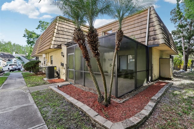 12736 Wood Trail Blvd, Tampa, FL 33625 - view of home's exterior featuring stucco siding, mansard roof, and cooling unit