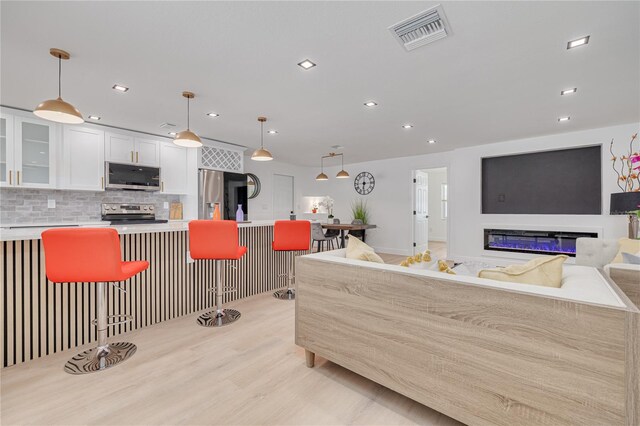 1717 Thames St, Clearwater, FL 33755 - kitchen featuring a kitchen breakfast bar, white cabinetry, visible vents, appliances with stainless steel finishes, and decorative backsplash