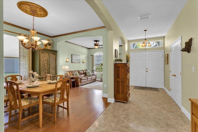 8202 Pinewood Run Ct, Tampa, FL 33647 - dining room featuring arched walkways, a chandelier, ornamental molding, a ceiling fan, and baseboards