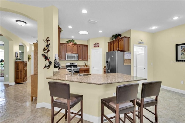 8202 Pinewood Run Ct, Tampa, FL 33647 - kitchen with appliances with stainless steel finishes, arched walkways, a peninsula, a kitchen bar, and recessed lighting