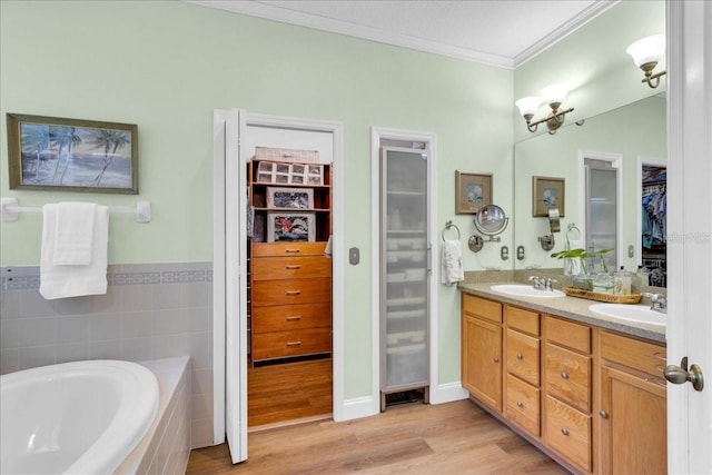 8202 Pinewood Run Ct, Tampa, FL 33647 - bathroom featuring ornamental molding, wood finished floors, double vanity, a garden tub, and a walk in closet