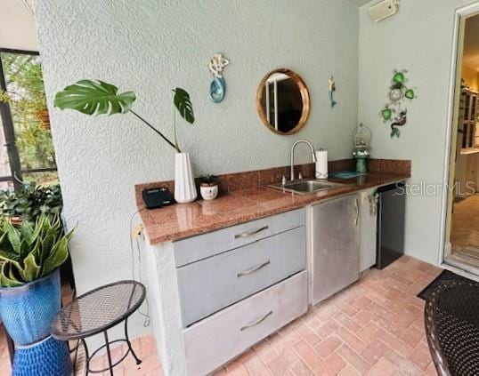 8202 Pinewood Run Ct, Tampa, FL 33647 - kitchen featuring black dishwasher, a sink, brick flooring, and a textured wall