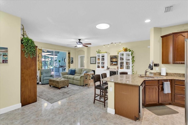 8202 Pinewood Run Ct, Tampa, FL 33647 - kitchen featuring a sink, ceiling fan, a peninsula, light stone countertops, and brown cabinetry