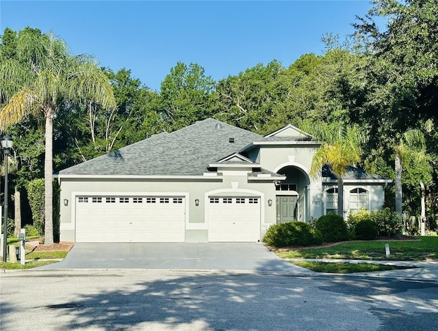 8202 Pinewood Run Ct, Tampa, FL 33647 - view of front of home with stucco siding, a garage, driveway, and a shingled roof