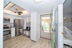 11720 Park Blvd Unit 301, Seminole, FL 33772 - kitchen featuring a ceiling fan, backsplash, white cabinets, appliances with stainless steel finishes, and light wood finished floors