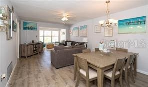 11720 Park Blvd Unit 301, Seminole, FL 33772 - dining area featuring wood finished floors, ceiling fan with notable chandelier, baseboards, and visible vents