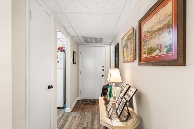 doorway to outside featuring a paneled ceiling, baseboards, wood finished floors, and visible vents