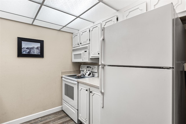 kitchen featuring white cabinets, dark wood-style floors, light countertops, white appliances, and baseboards