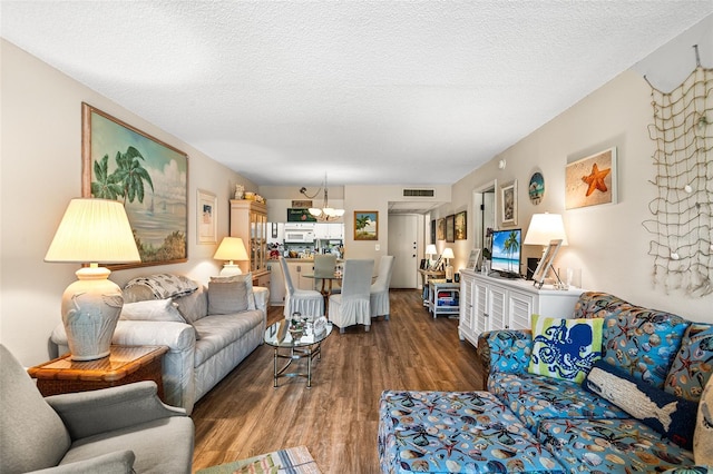 living area with dark wood finished floors, a notable chandelier, a textured ceiling, and visible vents