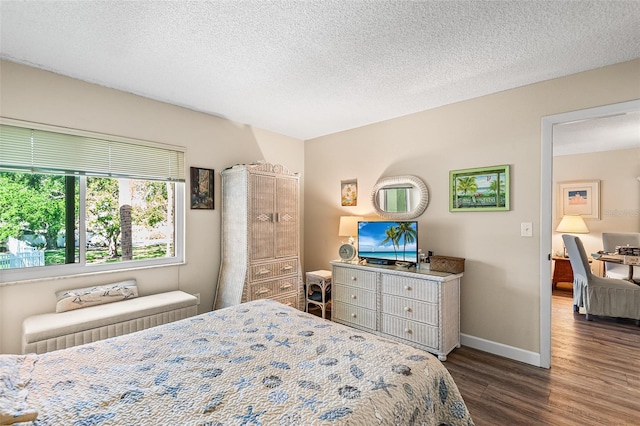 bedroom featuring baseboards, dark wood-style floors, and a textured ceiling
