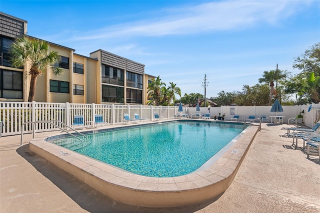 community pool with fence and a patio area