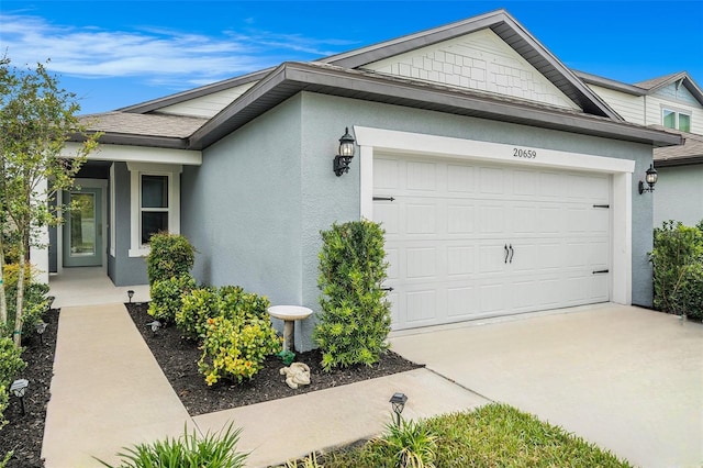 20659 Drake Elm Dr, Land O Lakes, FL 34638 - view of side of property with a garage, concrete driveway, stucco siding, and a shingled roof