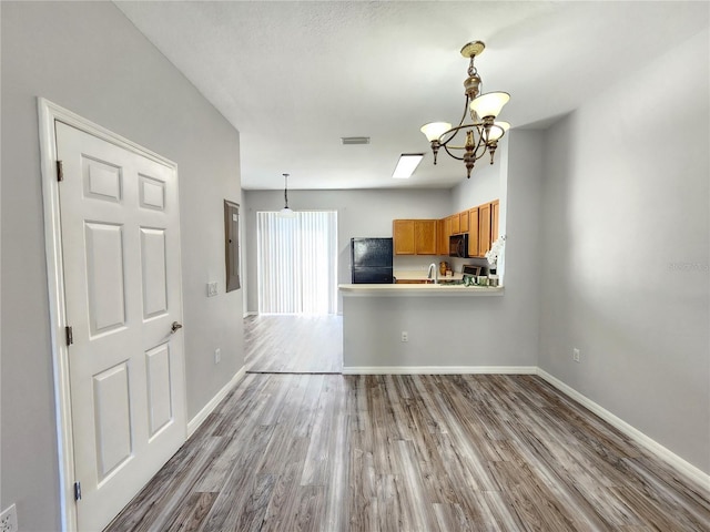 8796 Christie Dr, Largo, FL 33771 - unfurnished living room with a chandelier, wood finished floors, baseboards, electric panel, and a sink