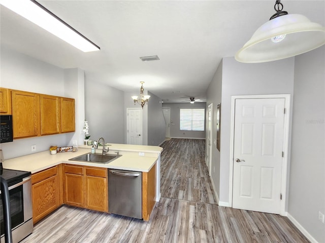 8796 Christie Dr, Largo, FL 33771 - kitchen with appliances with stainless steel finishes, a sink, light wood-type flooring, a peninsula, and a chandelier