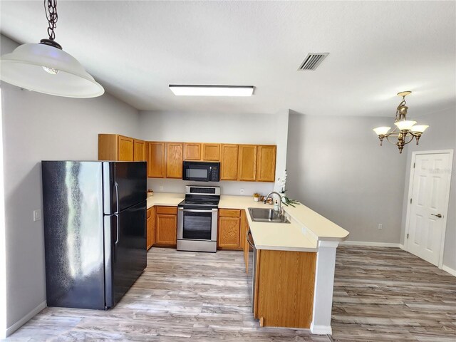 8796 Christie Dr, Largo, FL 33771 - kitchen featuring black appliances, a sink, a peninsula, brown cabinetry, and light countertops