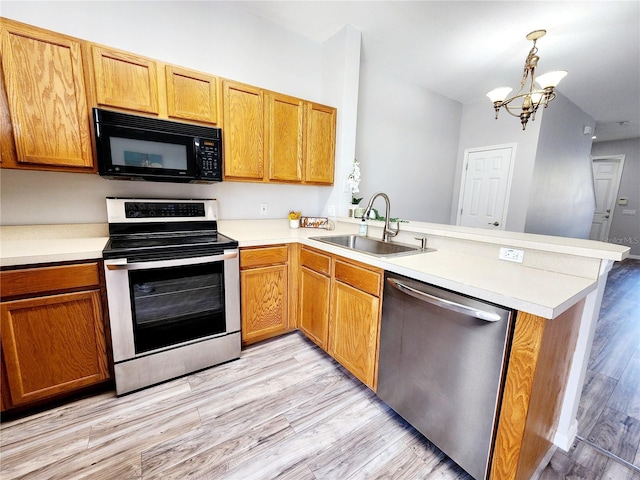 8796 Christie Dr, Largo, FL 33771 - kitchen featuring stainless steel appliances, a sink, a peninsula, a chandelier, and light wood-style floors