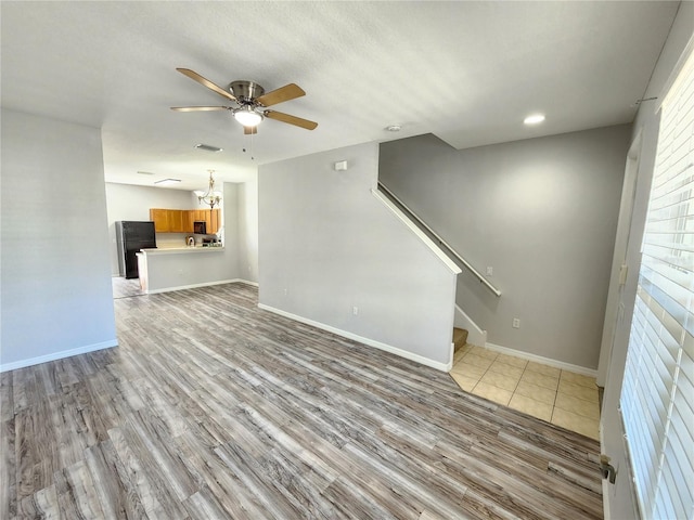 8796 Christie Dr, Largo, FL 33771 - unfurnished living room featuring a ceiling fan, light wood-style floors, stairway, baseboards, and a chandelier