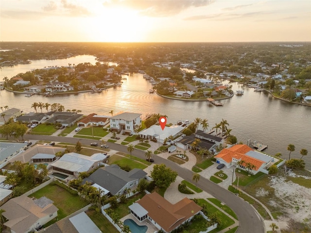 aerial view at dusk with a water view and a residential view