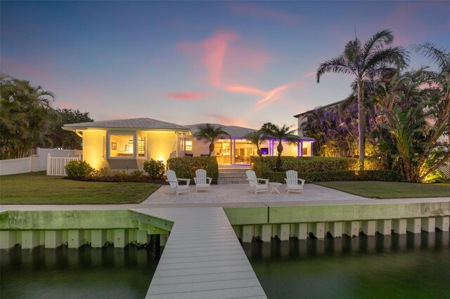 back of property at dusk with a patio area, fence, and a lawn