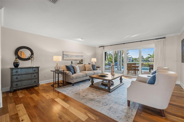 living room featuring ornamental molding, baseboards, and hardwood / wood-style floors