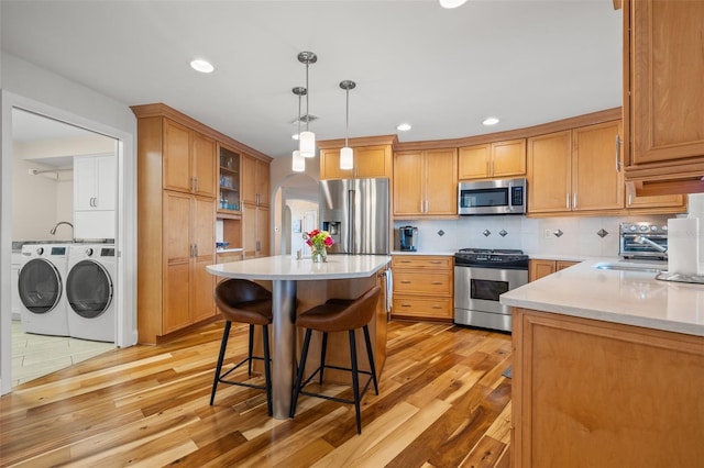 kitchen featuring separate washer and dryer, a kitchen breakfast bar, visible vents, stainless steel appliances, and arched walkways