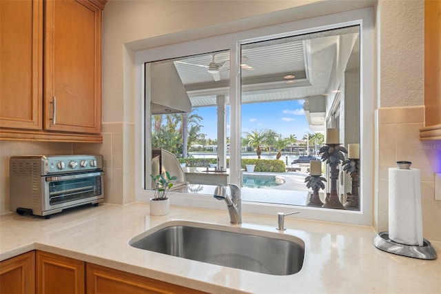 kitchen with a toaster, brown cabinets, a sink, and ceiling fan