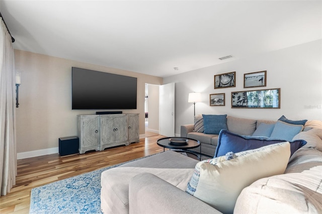 living area featuring visible vents, baseboards, and light wood finished floors