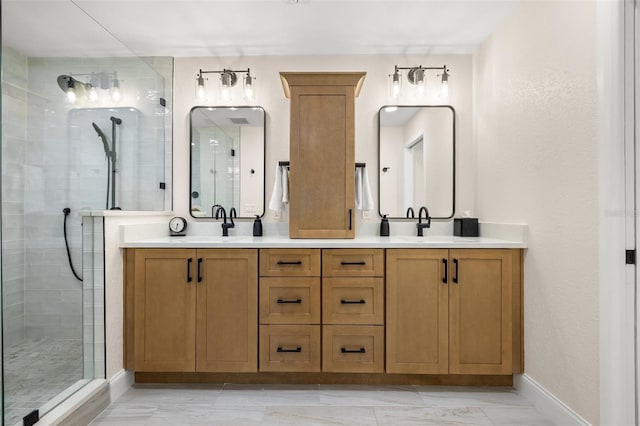 full bath featuring a tile shower, a sink, double vanity, and baseboards