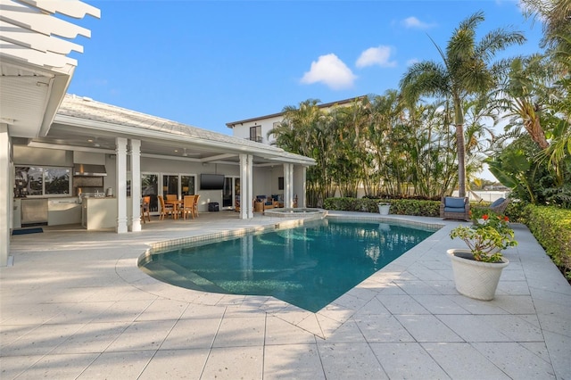 view of swimming pool with exterior kitchen, a patio area, outdoor dining area, and a pool with connected hot tub