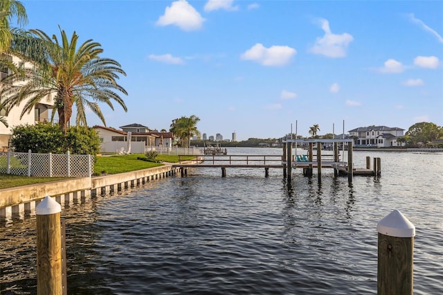 view of dock with boat lift, a residential view, fence, and a water view