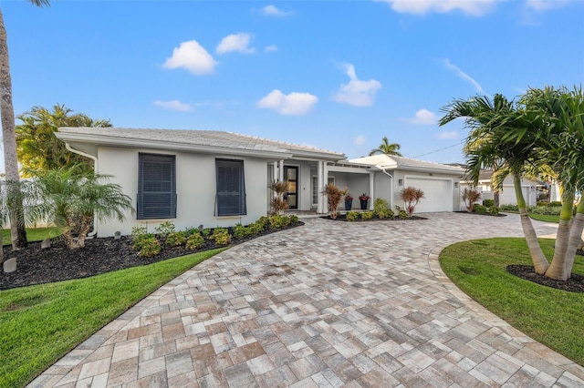 ranch-style house featuring a tiled roof, a garage, stucco siding, and decorative driveway