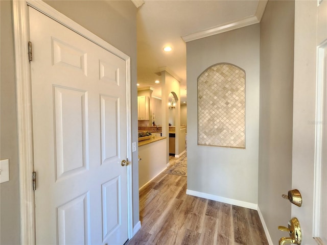 hallway featuring recessed lighting, light wood finished floors, crown molding, and baseboards