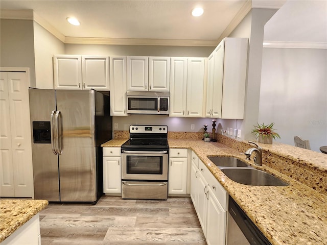 kitchen with light stone counters, a sink, stainless steel appliances, light wood finished floors, and ornamental molding