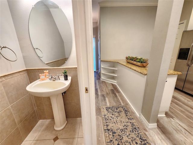 bathroom featuring tile walls, a wainscoted wall, wood finished floors, and crown molding