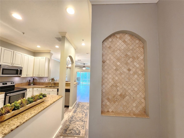kitchen with recessed lighting, light stone counters, stainless steel appliances, a sink, and white cabinetry