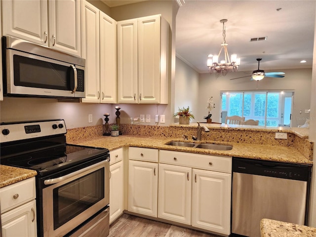 kitchen featuring stainless steel appliances, a sink, light wood-type flooring, ceiling fan with notable chandelier, and crown molding