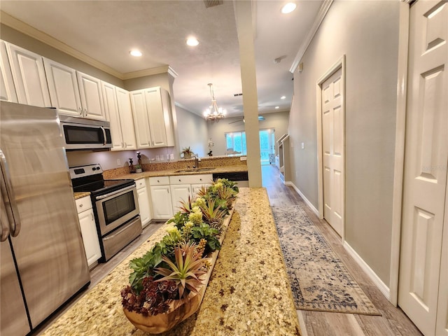 kitchen with light wood-style flooring, a sink, appliances with stainless steel finishes, and crown molding