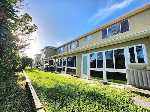 rear view of property featuring stucco siding and central AC