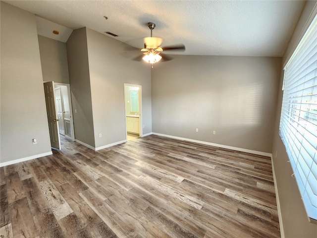 spare room with a textured ceiling, visible vents, baseboards, wood finished floors, and a ceiling fan