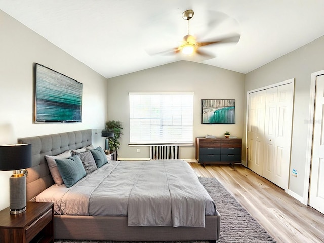 bedroom featuring radiator, lofted ceiling, light wood-style floors, baseboards, and ceiling fan