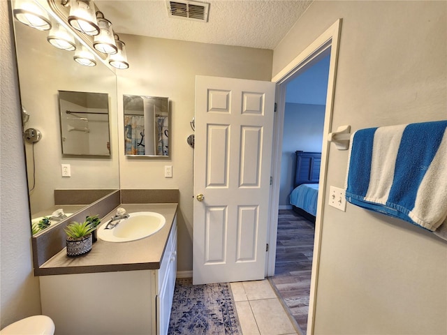 bathroom featuring tile patterned floors, a textured ceiling, vanity, toilet, and visible vents